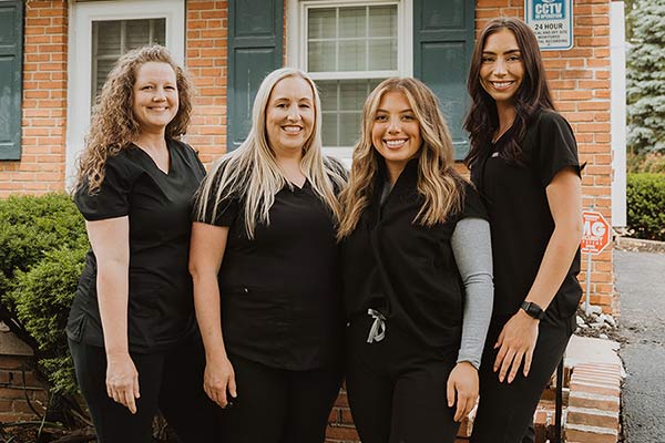 Image of all the assistants standing together in front of Cleary Dental office building.