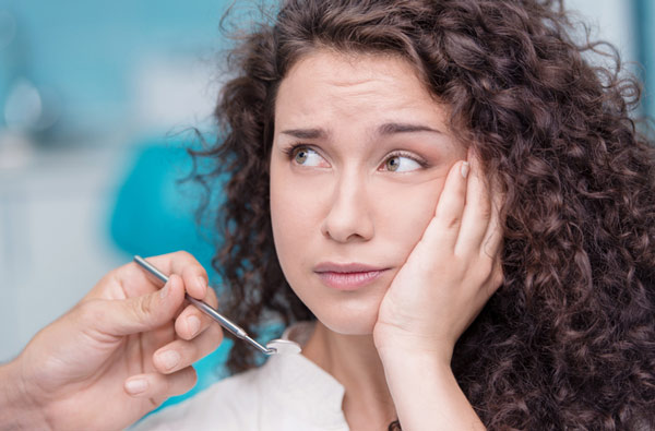 Woman holding cheek in pain before tooth extraction at Cleary Dental in Haddonfield, NJ.